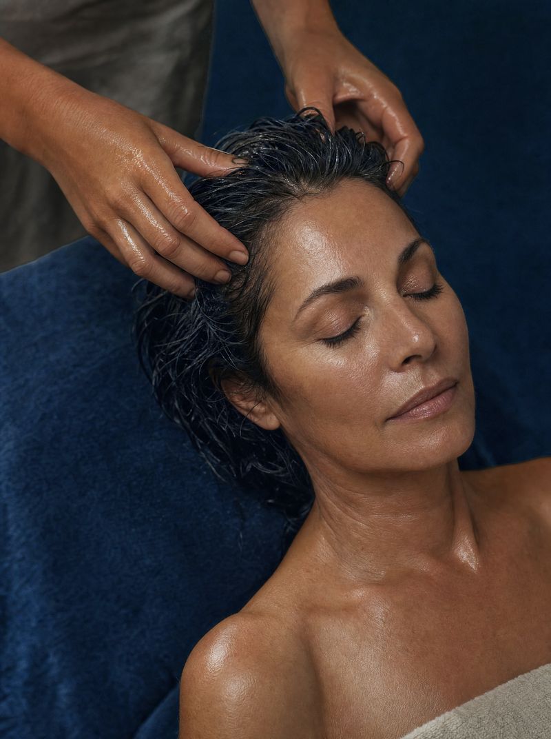 Woman reclining with wet hair as a therapist massages her scalp