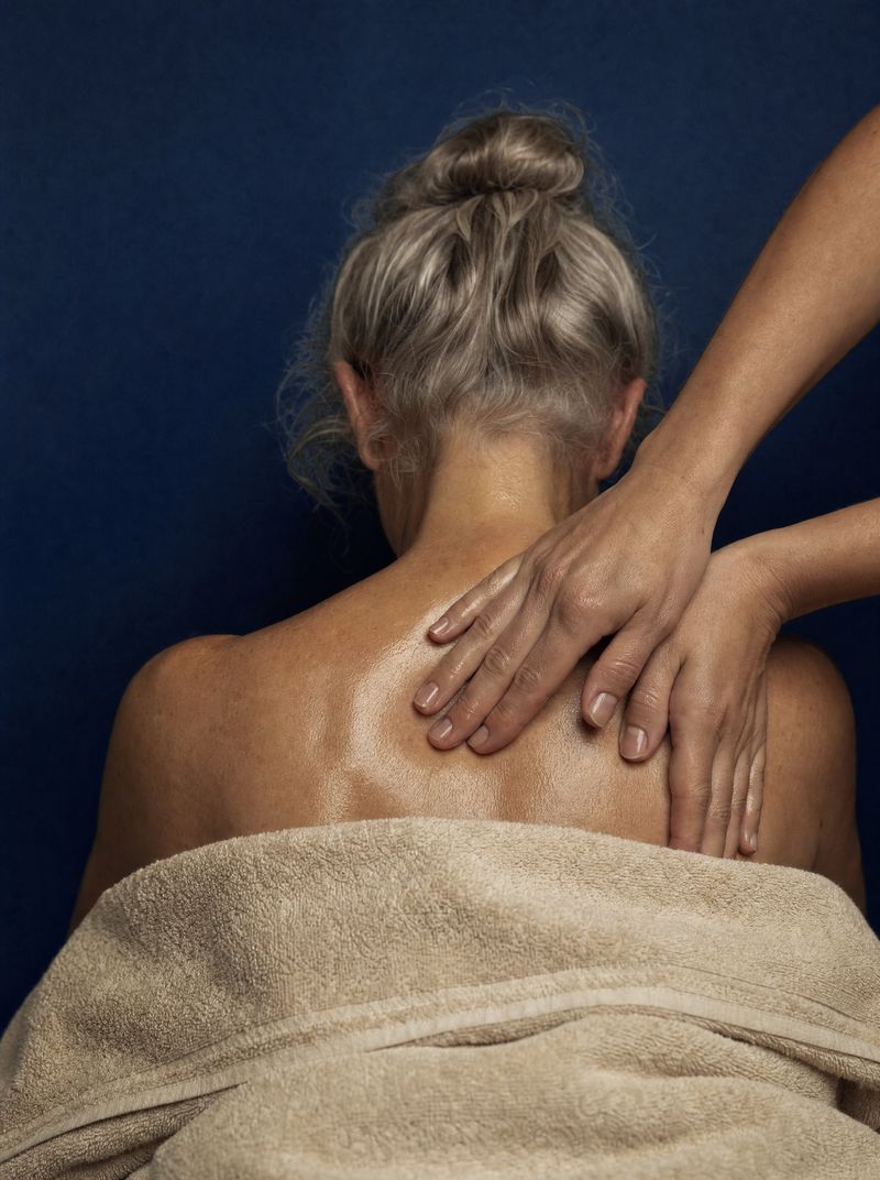 Therapist pressing warm oil into a guest’s shoulders