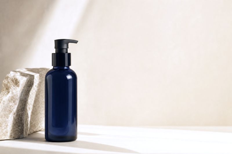 Navy glass pump bottle beside a pale stone